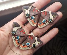 two butterflies are sitting on the palm of someone's hand with hoop earrings in it