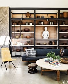 a living room filled with furniture and bookshelves next to a wall covered in shelves