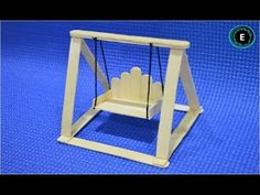 a wooden toy swing with two hands hanging from it's sides on a blue surface