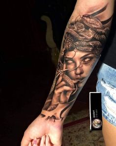 a woman with a snake tattoo on her arm holding the hand of a man's hand