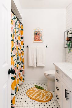 a white bathroom with orange and green decor on the shower curtain, toilet seat cover, and rug