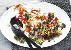 a white plate topped with broccoli covered in sauce next to a spatula