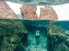 a person is swimming in the water near some rocks and rock formations on the ocean floor