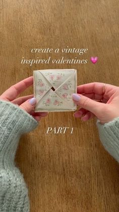 a person holding an envelope in front of a wooden table with the words create a vintage inspired valentine's day card