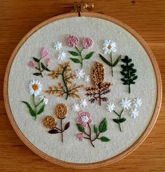 a close up of a embroidery on a wooden hoop with flowers and leaves in it