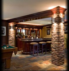 a pool table and some stools in a room with brick pillars on the wall