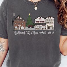 a woman wearing a t - shirt that says hallman christmas movie vibes on it