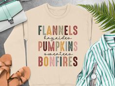 Celebrate the fall season with this graphic t-shirt, hoodie, or sweatshirt featuring fun sayings like flannels, hayrides, pumpkins, sweaters, and bonfires. Perfect for autumn vibes. Trendy Pre-shrunk Fall Sweatshirt, Fall Graphic Tee Sweatshirt With Funny Print, Fall Sweatshirt With Funny Print And Relaxed Fit, Fall Graphic Tee With Lettering, Cute Tshirt, Fun Sayings, Autumn Vibes, Fall Vibes, Fall Season