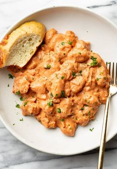 a white plate topped with macaroni and cheese next to a piece of bread