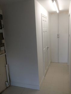 an empty hallway with white walls and tile flooring