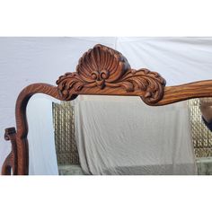 an ornate wooden bed frame with mirror on it's side and fabric draped in the background