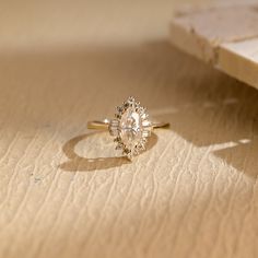 an oval shaped diamond ring sitting on top of a piece of paper next to a book