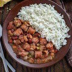 a brown plate topped with rice and beans next to a fork on top of a wooden table