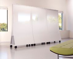 a room with white walls and black casteors on the floor next to a green bench