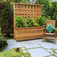 a wooden bench sitting in the middle of a garden next to a planter filled with flowers