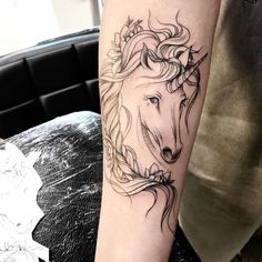 a woman's arm with a tattoo of a unicorn and flowers on the side