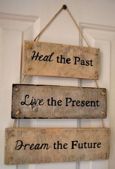 three wooden signs hanging from the side of a door that says, heal the past live the present dream the future