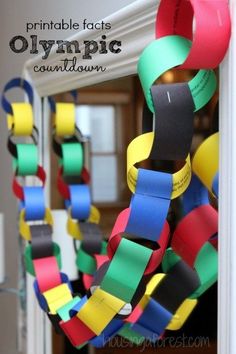 a wreath made out of strips of colored paper is hanging from the front door with words reading, printable fact olympic count down