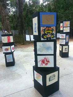 a group of art pieces sitting on top of a cement ground next to a forest