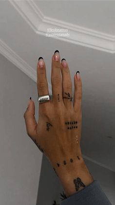 a woman's hand with black and white tattoos on her left wrist, holding onto the ceiling