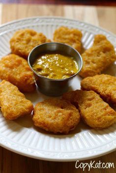 some fried food is on a plate with dipping sauce in the center and mustard in the middle