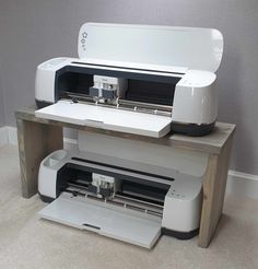 a white printer sitting on top of a wooden table next to a black and white machine