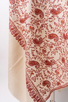 Adorned with intricate Sozni hand embroidery, the Sozni Blossom Whisper Pashmina Shawl is a luxurious tribute to the splendor of spring. The rich tapestry of crimson and amber florals blooms across an elegant cream backdrop, echoing the whispered tales of blooming gardens in the serene Kashmir valley. This shawl is a canvas of comfort, where each hand-stitched detail adds to the narrative of its craftsmanship. Draped over the shoulders, it offers a touch of warmth and sophistication, making it a Luxury Elegant Shawl With Chikankari Embroidery, Pashmina Shawl Embroidery Hands, Luxury Embroidered Cream Shawl, Kashmir Valley, Embroidered Rug, Kashmiri Shawls, Embroidered Handbag, Silk Carpet, Embroidered Wool