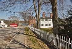 a fire truck is parked on the side of the road next to a white picket fence