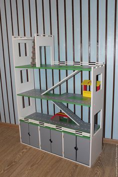 a toy truck is parked in front of a shelf with shelves and bins on it