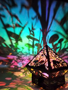 a lit up lantern sitting on top of a table next to a flower pattern wall