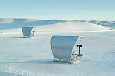 two chairs sitting in the snow next to each other on top of a flat field