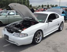 a white car with its hood open in a parking lot