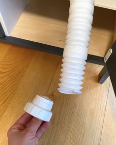 a hand holding a plastic cup in front of an open shelf with paper cups on it