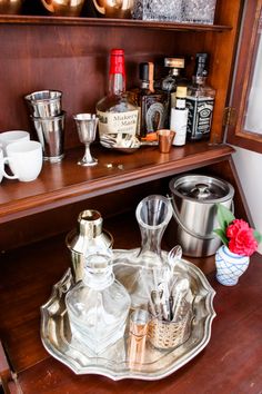 a wooden shelf filled with lots of bottles and silver dishes on top of it's sides