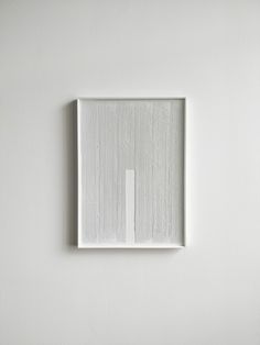 a white square with a rectangle in the middle is mounted on a wall,