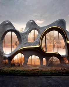 an unusual building with curved windows and gold trimmings on the outside, in front of a misty landscape