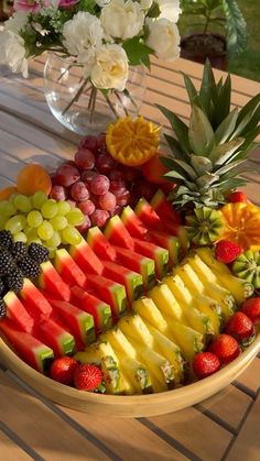 a bowl filled with lots of different types of fruit on top of a wooden table