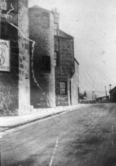 an old black and white photo of a street with buildings on the side of it