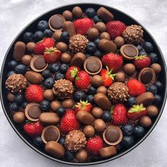 a bowl filled with chocolate covered strawberries and berries