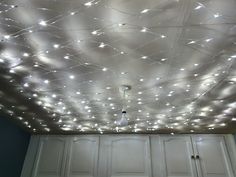 a kitchen with white cabinets and lights on the ceiling above it's cupboards