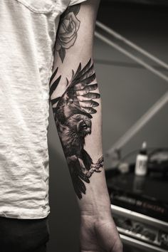 a man with a tattoo on his arm holding a bird in it's claws