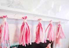 pink tassels hanging from clothes line on wall