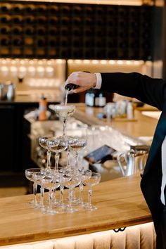 a man in a tuxedo pours wine into glasses on a bar counter