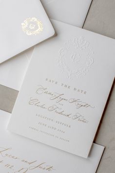 the wedding stationery is laid out on top of white envelopes with gold foil