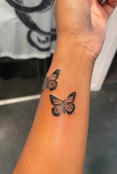 a woman's arm with two butterflies tattooed on the side of her left arm