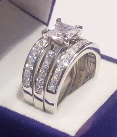 a couple of wedding rings sitting on top of a purple and white cloth covered box