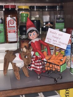 an elf is sitting on top of a shopping cart with carrots and a stuffed animal