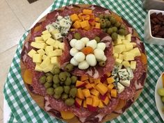 a platter of meat, cheese and olives on a green checkered tablecloth