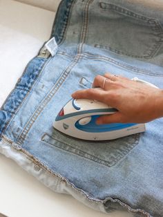 a person ironing jeans with an iron on it's back pocket and hand resting on top of the pants