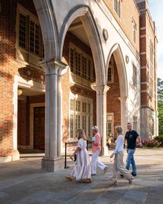 four children are walking in front of an old brick building with arched doorways and arches